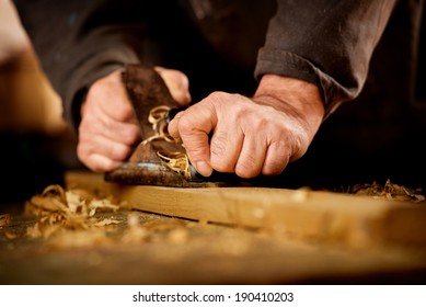 Senior man or carpenter doing woodworking planing the surface of a plank of wood in his workshop with a manual plane as he enjoys his creative hobby - Powered by Shutterstock