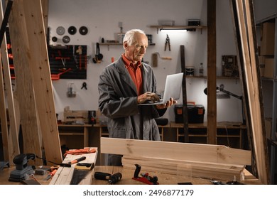 Senior man Carpenter Working In Woodwork Workshop Using Laptop Computer. Copy space - Powered by Shutterstock