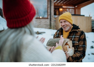 Senior man carrying wooden logs and preparing outdoor fire, during winter day. - Powered by Shutterstock