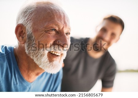 Senior man catching his breath while exercising with is adult son in nature.