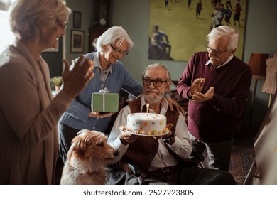 Senior man celebrating birthday with cake surrounded by friends and dog - Powered by Shutterstock