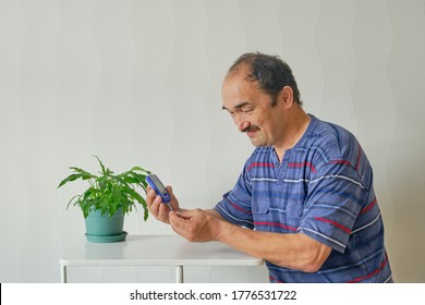 Senior Man Checking Blood Sugar Level At Home