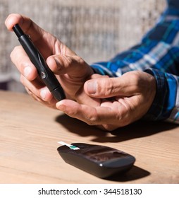 Senior Man Checking Blood Sugar Level At Home