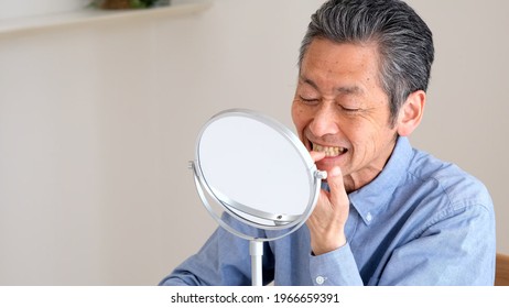 Senior Man Checking Teeth In The Living Room