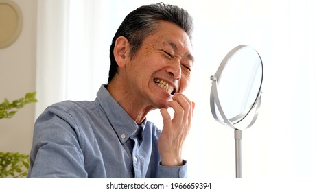 Senior Man Checking Teeth In The Living Room