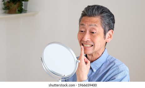 Senior Man Checking Teeth In The Living Room