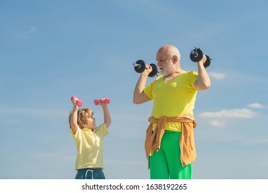 Senior Man And Child In Family Health Club. Sportsman Grandfather And Healthy Kid With Dumbbell Exercise. Grandfather And Child Do Morning Exercise