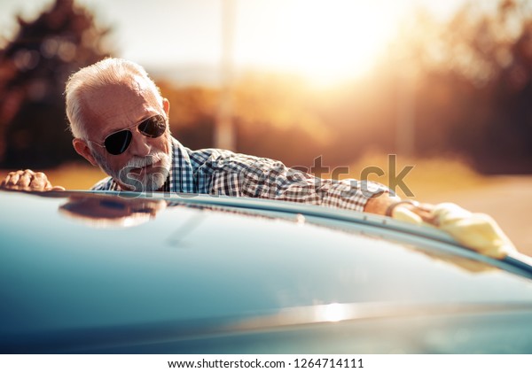 Senior man cleaning his
car outdoors.