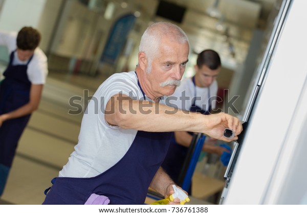 senior man cleaning a\
school