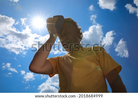 Senior man with cold pack suffering from heat stroke outdoors, low angle view