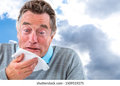 Senior Man With A Common Cold Blowing His Nose With A Tissue