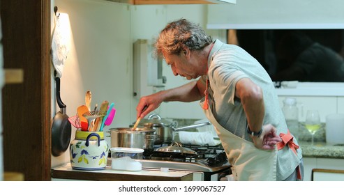 
Senior Man Cooking At The Kitchen. Candid Older Retired Person Stirring Pot