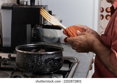 Senior Man Cooking A Stew With Wooden Fork