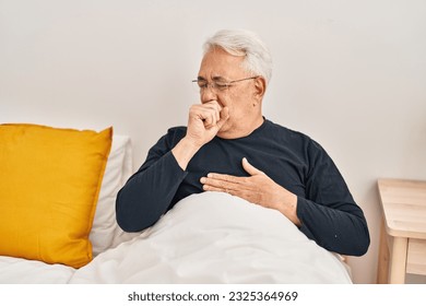 Senior man coughing sitting on bed at bedroom - Powered by Shutterstock