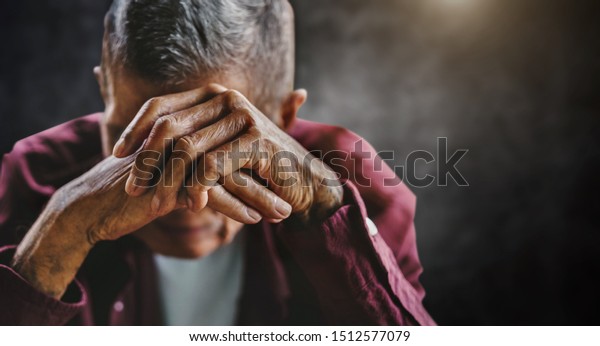 senior man covering his face\
with his hands. Depression and anxiety Copy space. in dark\
background