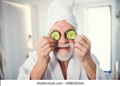 Senior man with cucumber on front of his eyes in bathroom indoors at home.