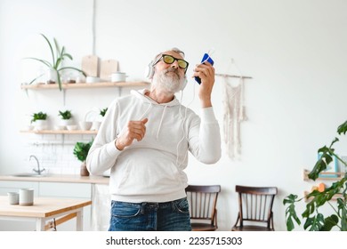Senior man dance and using smartphone app for creating playlist music on mobile app - Elderly male having fun dancing with mobile phone technology - Tech and joyful elderly lifestyle concept