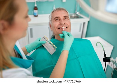 Senior Man In Dental Chair With Female Dentist Compare Dental Color For Dentures