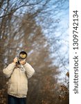 Senior man devoting time to his favorite hobby - photography - taking photos outdoor with his digital camera/DSLR and a big telephoto lens