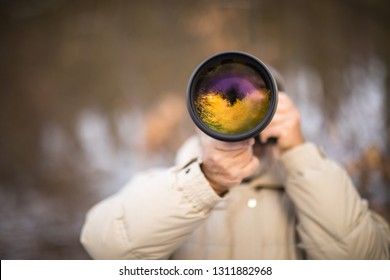 Senior man devoting time to his favorite hobby - photography - taking photos outdoor with his digital camera/DSLR and a big telephoto lens