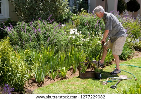Senior man digging in flower bed working in garden
