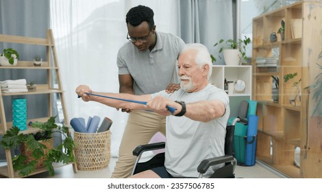 Senior man with disability, physiotherapist and stretching band for muscle rehabilitation, chiropractor service or help. Physical therapy, medical support or patient in wheelchair at recovery clinic - Powered by Shutterstock