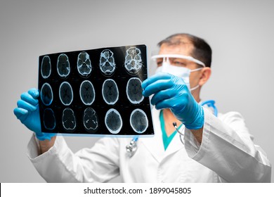 Senior Man Doctor In Mask Examines Head MRI In Hospital