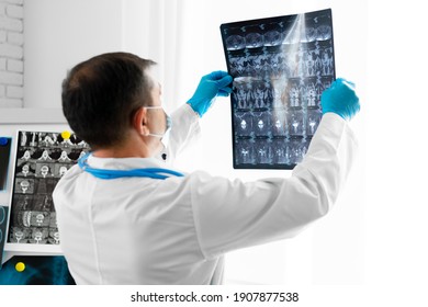 Senior Man Doctor In Mask Examines Head MRI In Hospital