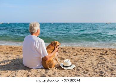 Senior Man With Dog In White Suit Sitting At The Beach 