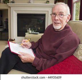 Senior Man Doing Crossword On Sofa