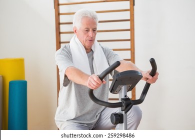 Senior Man Doing Exercise Bike In Fitness Studio