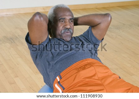 Senior man doing sit-ups on a pilates ball