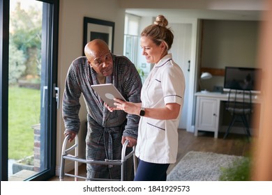 Senior Man In Dressing Gown Using Walking Frame Being Helped By Female Nurse With Digital Tablet - Powered by Shutterstock