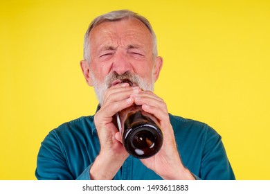 Senior Man Drinking Alcohol Alone Studio Yellow Baclground.