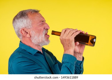 Senior Man Drinking Alcohol Alone Studio Yellow Baclground.