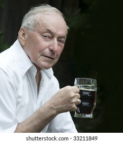 Senior Man Drinking A Beer Outside Of Pub.