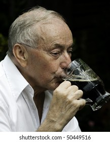 Senior Man Drinking A Beer Outside Of Pub.