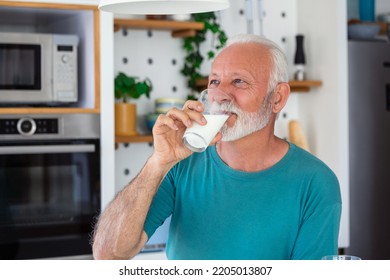 Senior man drinking a glass of milk with a happy face standing and smiling. Handsome senior man drinking a glass of fresh milk in the kitchen - Shutterstock ID 2205013807