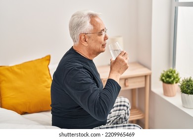 Senior Man Drinking Glass Of Water At Bedroom