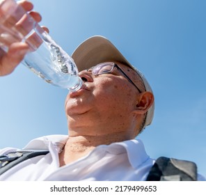 A Senior Man Drinking Plenty Of Water On A Record Breaking Hot Summer Day To Avoid Dehydration While Out And About.