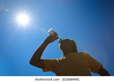 Senior man drinking water to prevent heat stroke outdoors, low angle view - Powered by Shutterstock