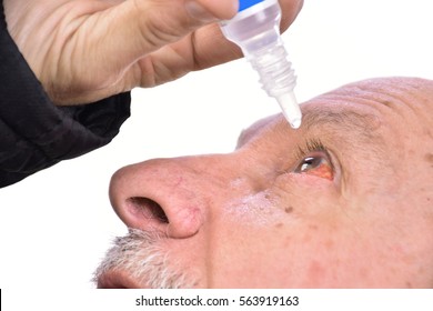 Senior man dripping a red bloodshot  eye with eye drops on a white background. Close-up image