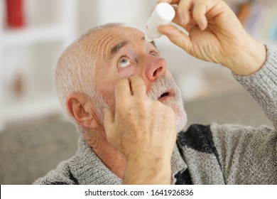 Senior Man Dripping A Red Eye With Eye Drops