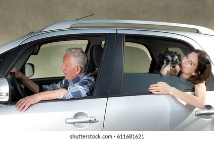 Senior Man Driving Car With His Granddaughter Sitting Behind With Dog, Looking Through Window