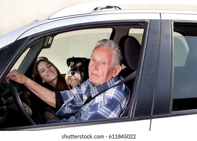 Senior Man Driving Car With His Granddaughter And Dog Beside Him, Looking Through Window