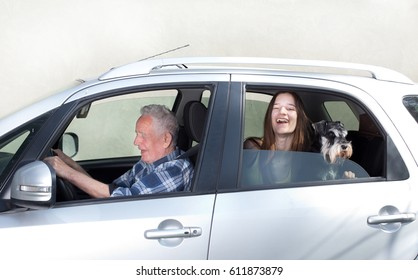 Senior Man Driving Car With His Granddaughter Sitting Behind With Dog, Looking Through Window