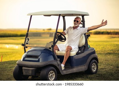 Senior Man Driving Golf Car And Waving.