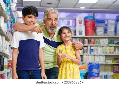 Senior man enjoying shopping to his grandson and granddaughter at grocery shop. - Powered by Shutterstock