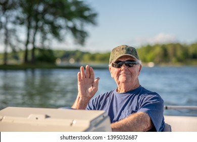 A Senior Man Enjoys Driving A Boat On A Beautiful Lake On A Sunny Day.