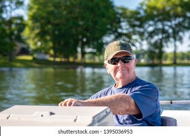 A Senior Man Enjoys Driving A Boat On A Beautiful Lake On A Sunny Day.